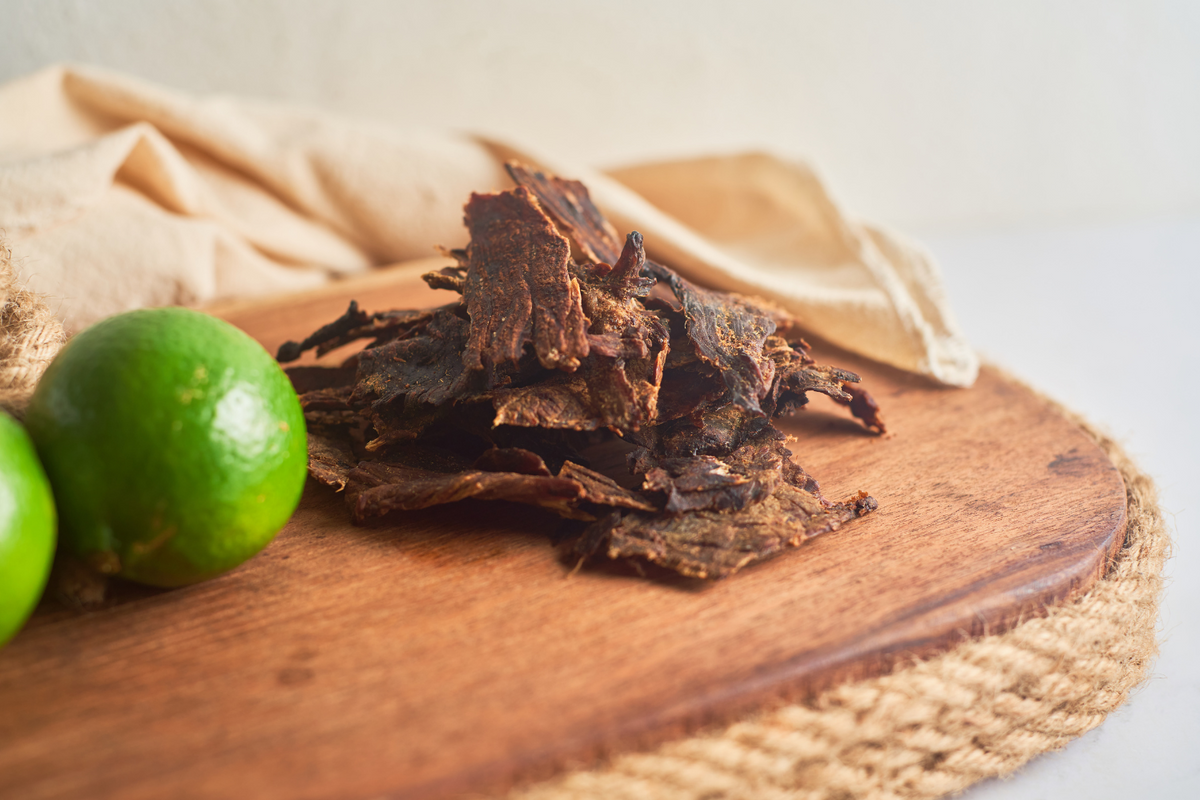 Slices of beef jerky on a wooden surface.