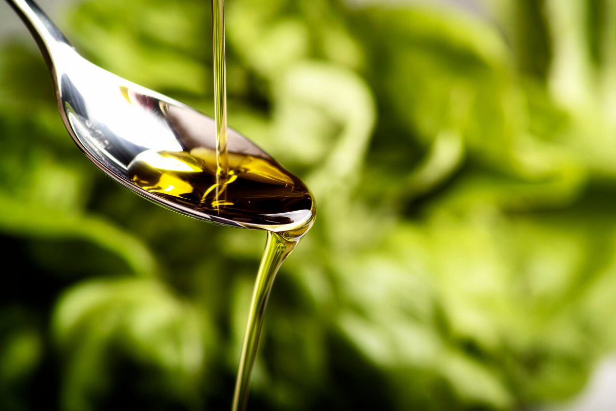 Olive oil pouring on a spoon.