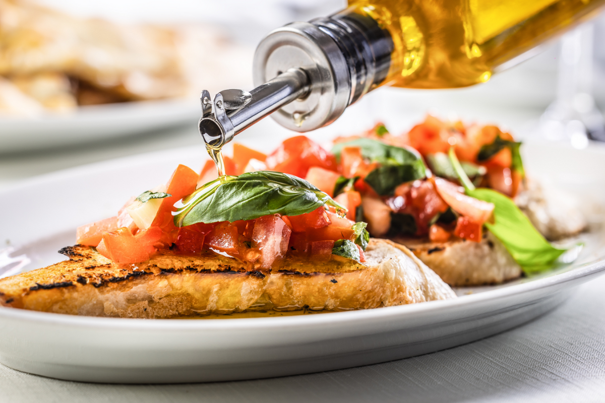 A bottle of extra virgin olive oil drizzled over a keto-friendly meal.