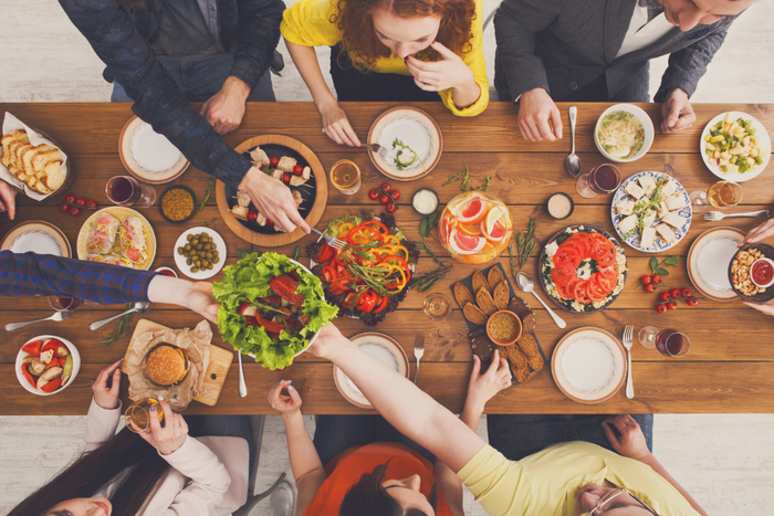 A group of people gathered around a large wooden table sharing a healthy meal.