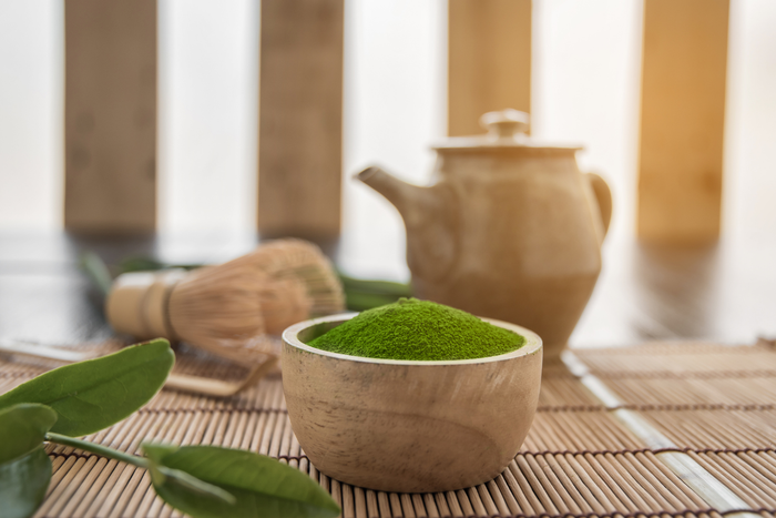 A wooden bowl of matcha powder on the table.