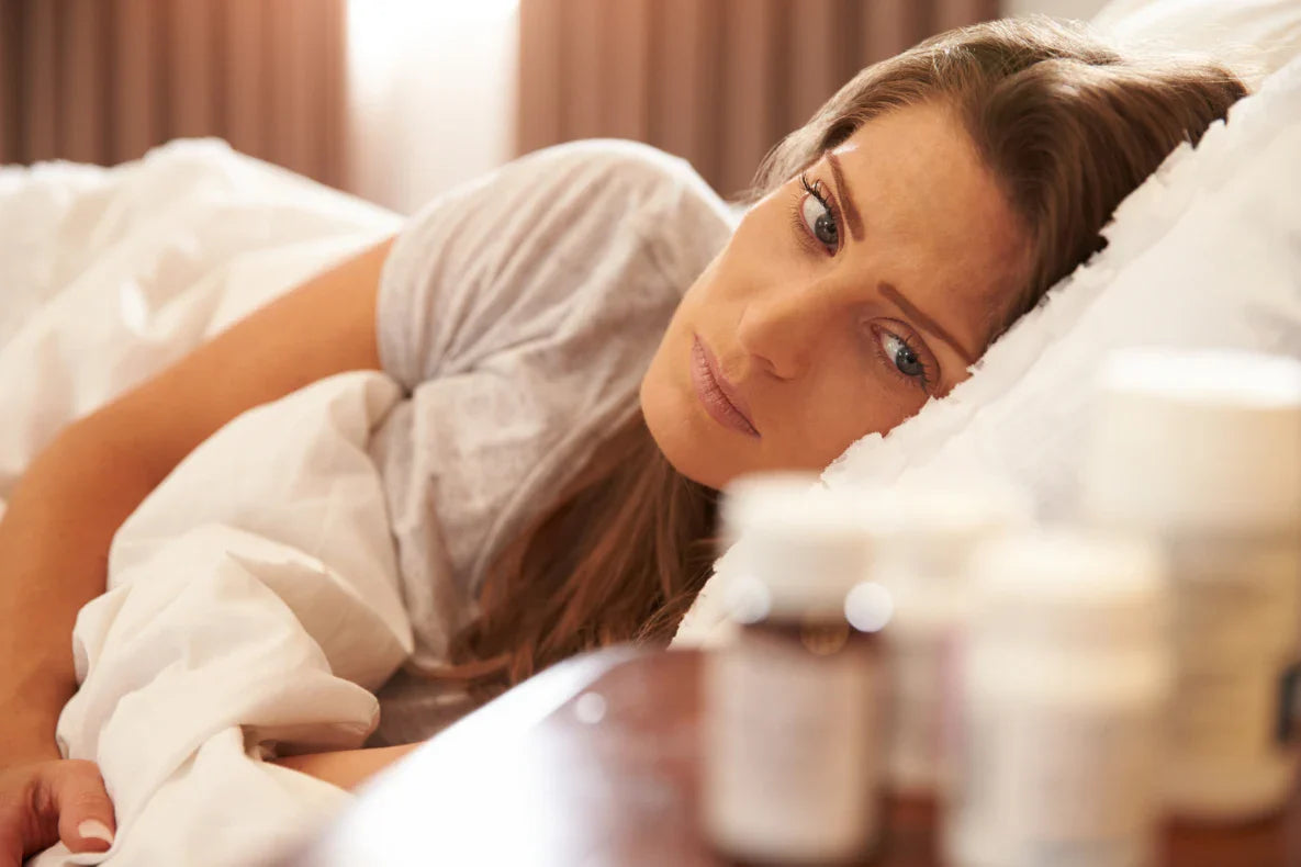 Woman looks at the bottles on the bed side table.