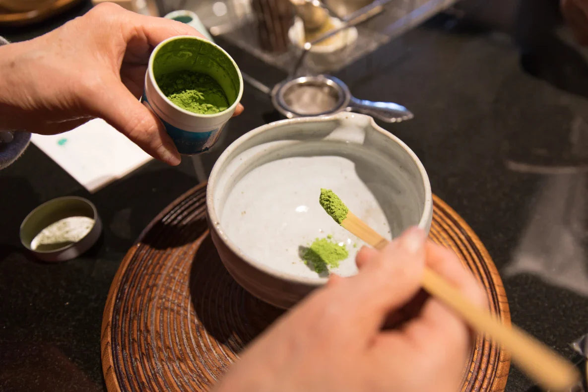 Hand putting some matcha to the bowl.
