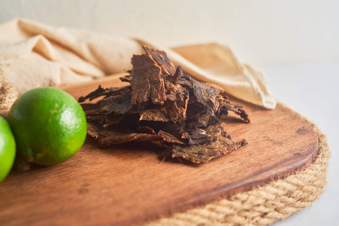 Slices of beef jerky on a wooden surface.