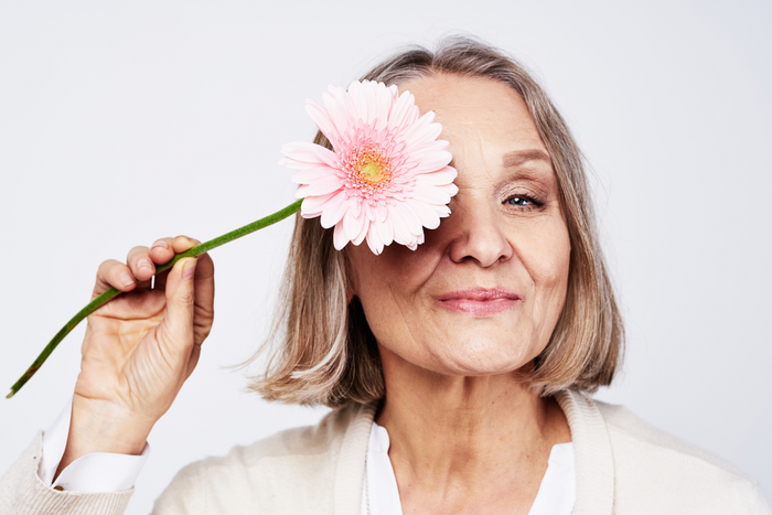 Older woman smiling with flower.