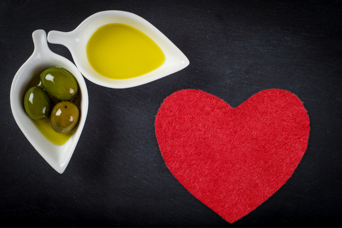 Olive oil on bowls and a heart on a black surface.