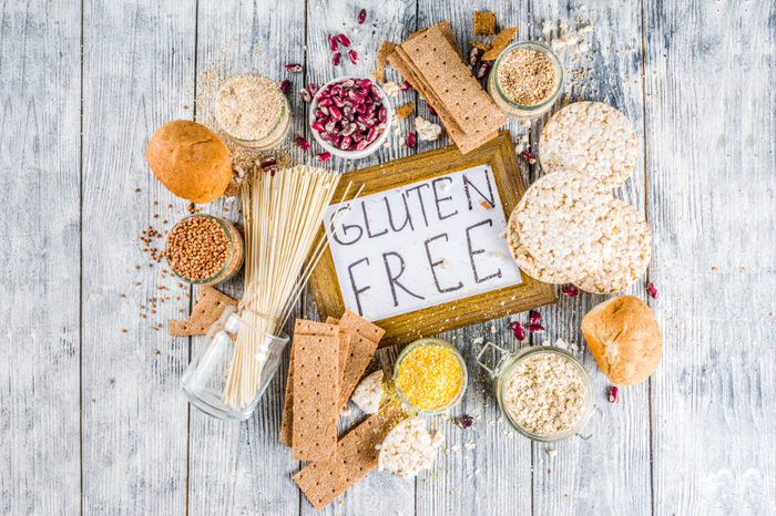 Assorted gluten-free grains and snacks including rice cakes, oats, crackers, and pasta with a gluten-free sign