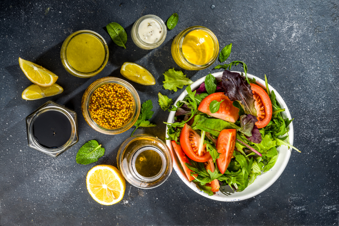 A healthy meal with salad, olive oil dressing, and lemon wedges arranged on a table.