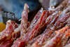 Close-up of cured beef jerky strips hanging during preparation, highlighting real meat quality in healthy jerky brands.