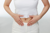 Person pointing to their stomach, representing melatonin absorption, empty-stomach timing, and how food may affect how quickly melatonin works.