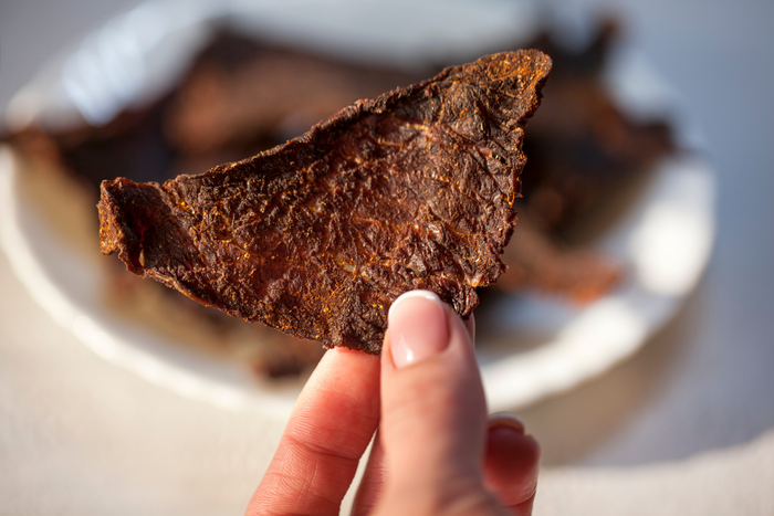 Person holding a piece of beef jerky.