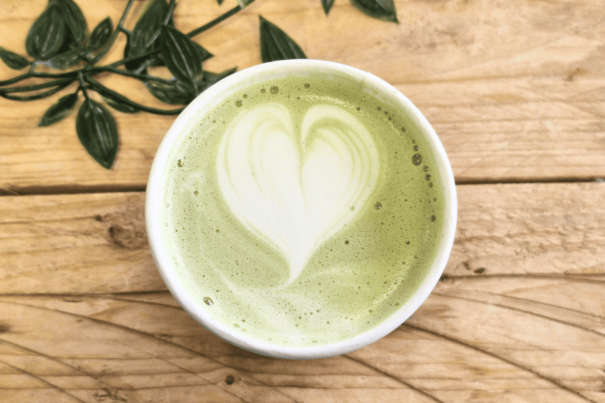 Cup of matcha green tea on a wooden table.