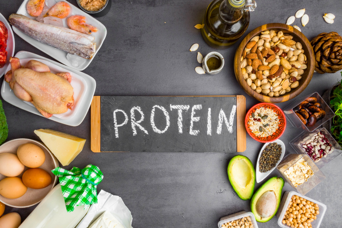 Fresh protein sources like chicken, beef, fish, cheese, lentils, and chickpeas on a wooden table