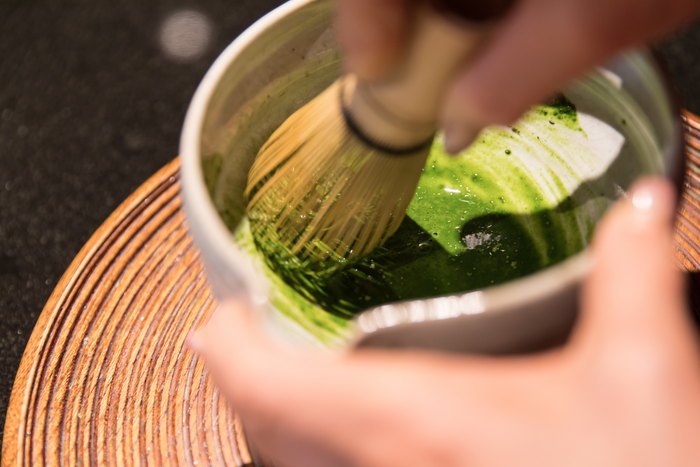 Person whisking matcha powder.