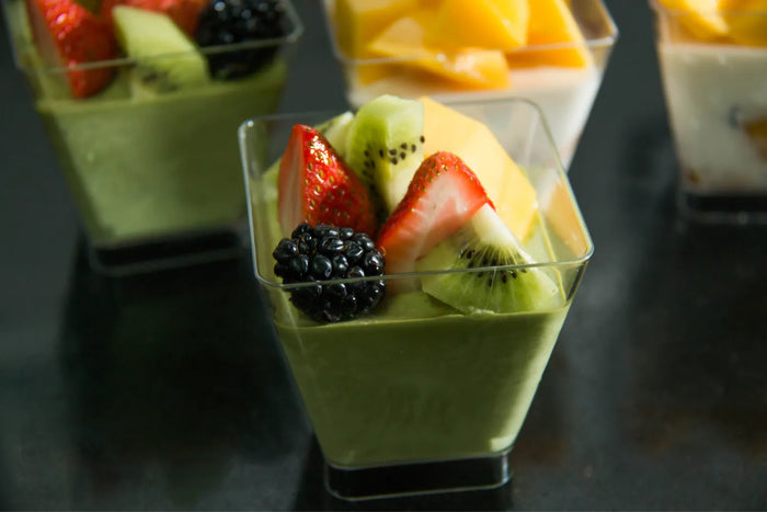 Small cups of green matcha mousse topped with strawberry, kiwi, blackberry, and mango.
