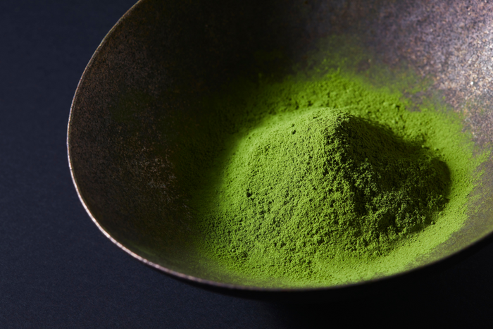 Bright green matcha powder on ceramic bowl.