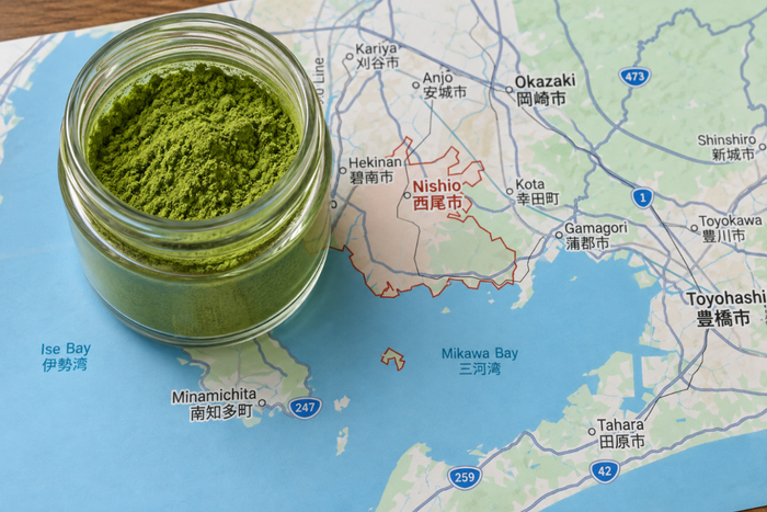 Jar of green Nishio matcha powder on a map of Aichi Prefecture, Japan.