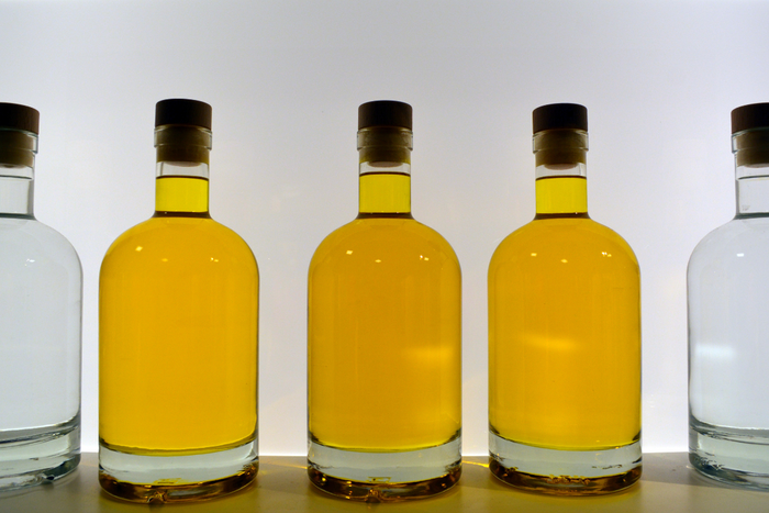 Different shades of certified olive oil in clear bottles for color comparison and quality control