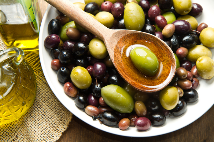 Mixed olives in a bowl with extra virgin olive oil on the side