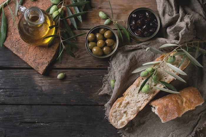 Rustic setup with organic extra virgin olive oil, fresh bread, and green olives