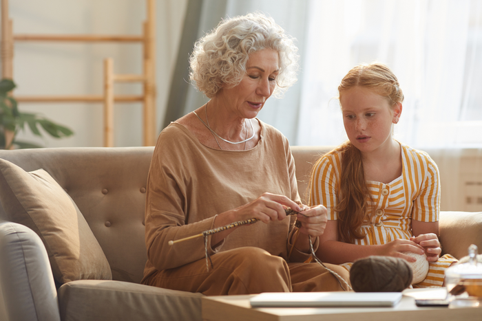 Grandmother teaching child how to knit.
