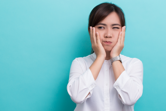 Woman swishing oil in her mouth with hands on cheeks during oil pulling
